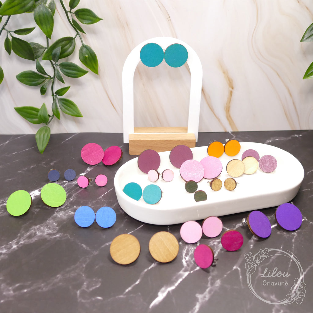 Boucles d’oreilles clous Iris en bois – présentation de plusieurs coloris sur présentoir et plateau