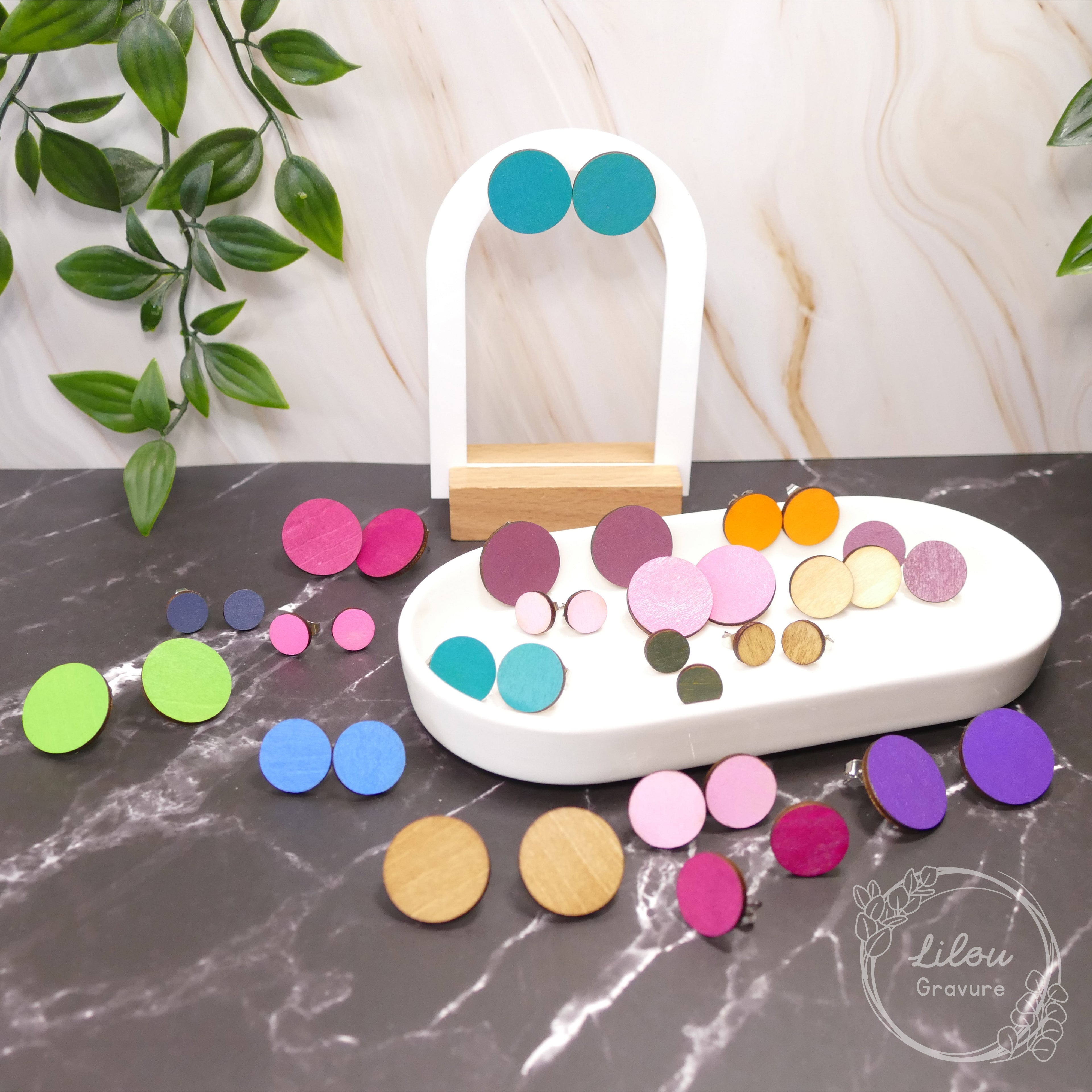 Boucles d’oreilles clous Iris en bois – présentation de plusieurs coloris sur présentoir et plateau